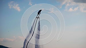 Extreme loving man is driving on flyboard over sea in summer vacation, lifting up by two water flows