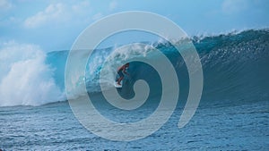 Extreme male rider surfing in breathtaking Tahiti catches a big emerald wave.