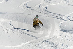 extreme man actively snowboarding on deep snow of mountain slope in winter