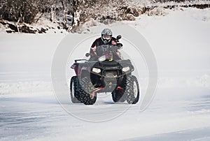extreme Moto rider in gear on the ATV in the winter in the snow
