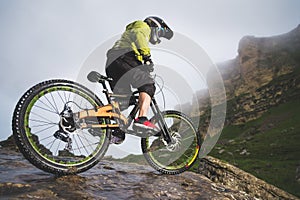 Extreme mountain bike sports athlete man in helmet riding outdoors against a background of rocks. Lifestyle. Trial