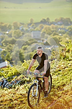 Extreme mountain cyclist riding bike on rocky trail at sunshiny day.