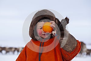 The extreme north, Yamal, the pasture of Nenets people, girl playing with an orange covering one eye