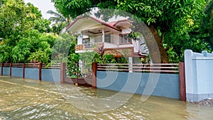 Extreme rainfall floods a road and threatens the front yard and garden of a house in the Philippines. photo
