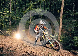 Extreme rider climbing rocky hill in the forest photo