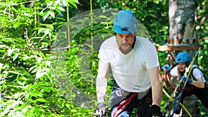 Extreme rope adventure - man and woman walking on the suspension rope bridge in the park