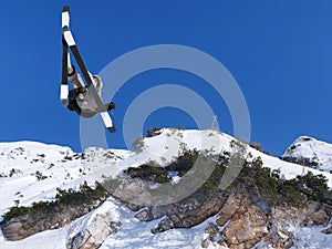 Extreme skier jumping from mountain sky in backgraund
