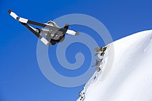 Extreme skier jumping from mountain sky in backgraund