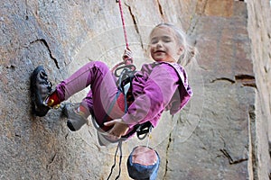 Extreme sport, active lifestyle, kid with a rope engaged in the sports of rock climbing on the rock