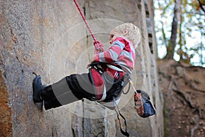 Extreme sport, active lifestyle, kid with a rope engaged in the sports of rock climbing on the rock