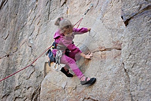 Extreme sport, active lifestyle, kid with a rope engaged in the sports of rock climbing on the rock