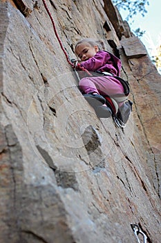 Extreme sport, active lifestyle, kid with a rope engaged in the sports of rock climbing on the rock