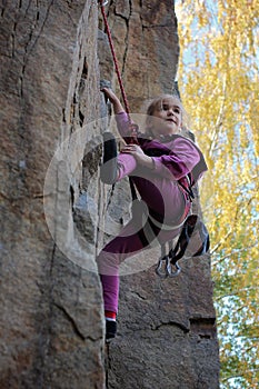 Extreme sport, active lifestyle, kid with a rope engaged in the sports of rock climbing on the rock