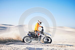 Extreme sport, motorcycle and athlete with sand by wheels with pride, skill and adrenaline rush. Biker, sunshine and