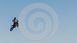 Extreme sports concept. Bike rider jumping high in the air. Wide panoramic shot. Blue sky as a background.