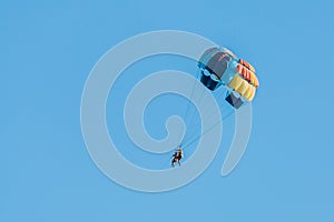 Extreme sports and exciting rest activity. Vacationing tourists fly on a parashute in blue sky background