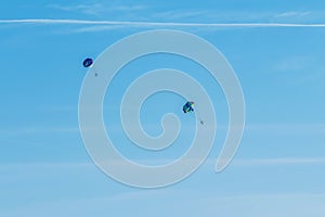 Extreme sports and exciting rest. Two tourists fly on a parashute in the blue sky background