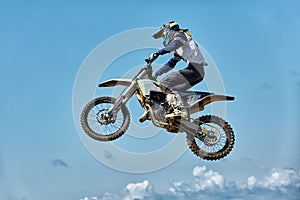 Extreme sports, motorcycle jumping. Motorcyclist makes an extreme jump against the sky. Film grain effect, illumination