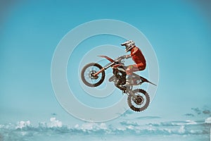 Extreme sports, motorcycle jumping. Motorcyclist makes an extreme jump against the sky. Film grain effect, illumination