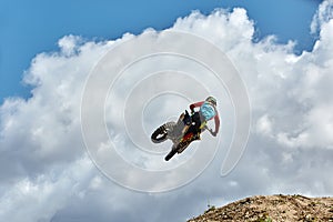 Extreme sports, motorcycle jumping. Motorcyclist makes an extreme jump against the sky. Film grain effect, illumination