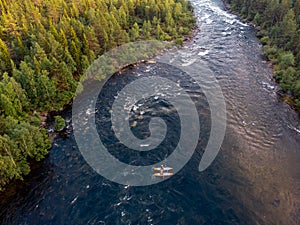 Extreme sportsmen are kayaking and rafting on mountain river in forest. Aerial top view