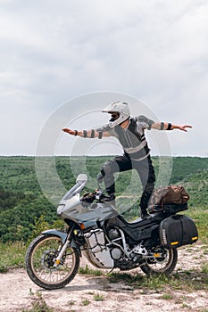 Extreme stunt on a bike. Like surfing. Motorcycle driver wearing a turtle jacket, body armor and a helmet. Stands on top. Vertical