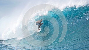 Extreme surfer drags his hand through the refreshing water while riding a wave.