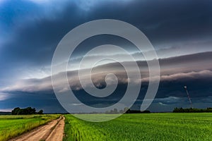 Extreme thunderstorm shelf cloud moving over fields, climate change concept