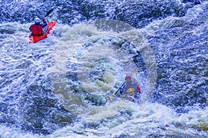 Extreme whitewater rafting trip. A group of people team in kayaks practise traversing the water rapids. Kayaker paddling on the