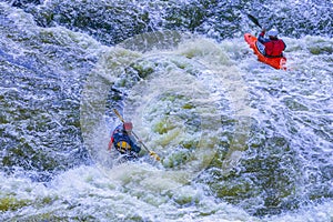 Extreme whitewater rafting trip. A group of people team in kayaks practise traversing the water rapids. Kayaker paddling on the