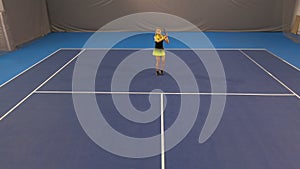 Extreme wide shot of confident beautiful sportswoman hitting ball with racket on indoor tennis court in gym. Portrait of
