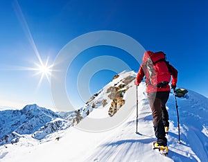 Extreme winter sports: climber at the top of a snowy peak in the