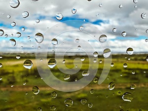 Extremely close up macro drops of water on a wet glass on natural green background. Raindrops pattern. Rainy day. Summer