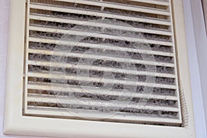 Extremely dirty and dusty white plastic ventilation air grille at home close up, harmful for health, house cleaning concept