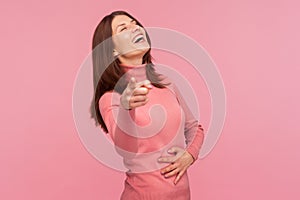Extremely excited happy woman laughing out loud holding her belly and pointing finger at camera, wondering and mocking