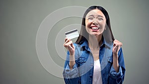 Extremely happy asian woman holding credit card, low interest rate for crediting