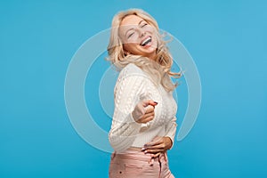 Extremely happy blond woman laughing out loud pointing finger, making fun of you and looking at camera, joke