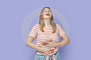 Woman holding her stomach and laughing out loud, chuckling giggling at amusing anecdote. photo