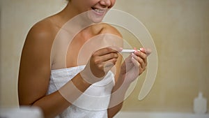 Extremely happy lady smiling and looking at two bars on pregnancy test after ivf