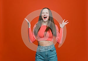 Extremely happy modern young teen girl screaming for joy, raised hands, closed eyes, celebrating successful win