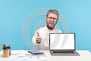 Extremely happy satisfied bearded man office manager showing thumbs up sitting at workplace with empty screen laptop, satisfied