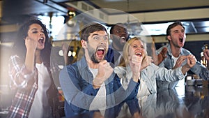 Extremely happy sport fans actively cheering team, celebrating victory in bar