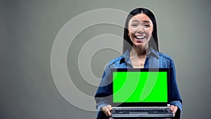 Extremely happy woman holding laptop with green screen, big winnings online