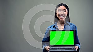Extremely happy woman holding laptop with green screen, big winnings online photo