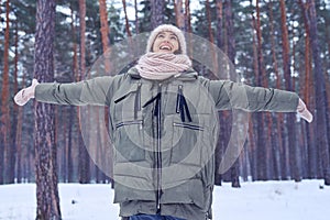 Extremely happy woman rejoices nice wintry weather in the forest