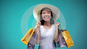 Extremely happy woman in white hat holding many paper bags, shopping addicted