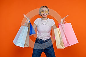 Extremely happy woman in white t shirt and jeans standing with shopping bags