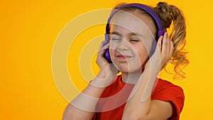 Extremely joyful child listening to music in headphones, enjoying favorite song