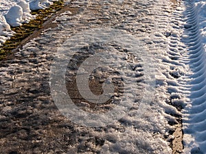 Extremely slippery footpath covered with melting snow and visible frozen ice footprints after heavy snowing in city in winter.