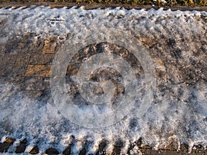 Extremely slippery footpath covered with melting snow and visible frozen ice footprints after heavy snowing in city in winter.